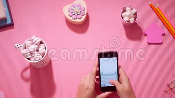 顶视图女孩用粉红色在智能手机上写短信视频的预览图