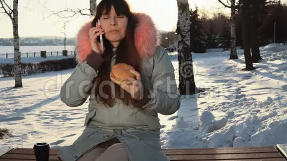年轻女子在冬季街头吃汉堡视频的预览图