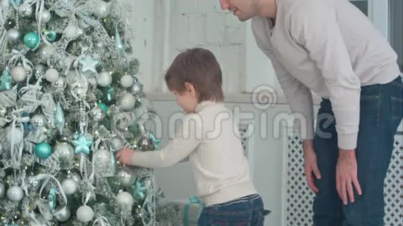 父子俩在客厅里用装饰圣诞树视频的预览图