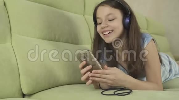 戴着耳机唱着卡拉OK歌的漂亮少女在智能手机股票录像中视频的预览图
