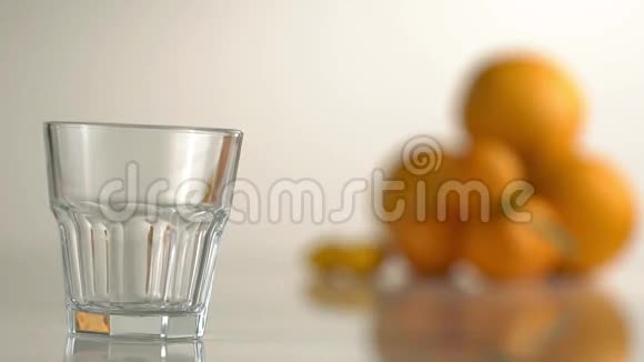 橘子饮料正在橘子和曼达林模糊的背景下倒入岩石玻璃中特写镜头视频的预览图