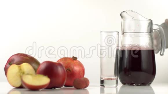 水果由苹果和石榴组成放在空玻璃附近那个人正在倒红果汁视频的预览图