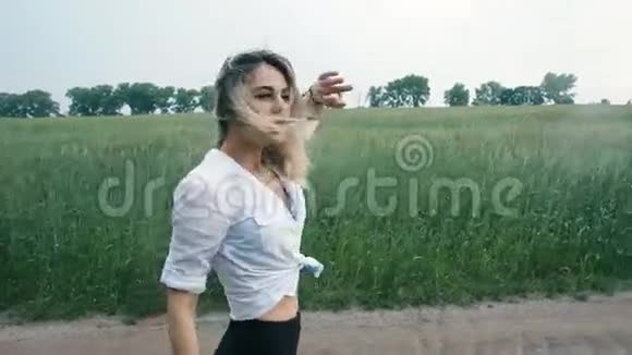 金发的运动女孩在田野里迎风而飞视频的预览图