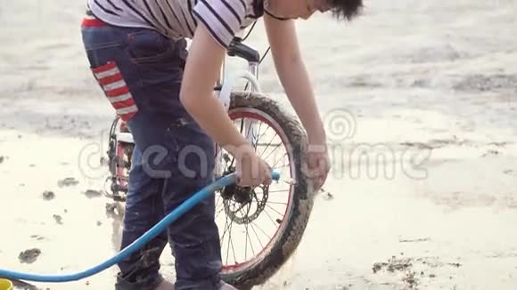 快乐的亚洲男孩用水管洗自行车视频的预览图
