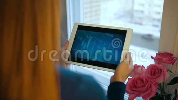 女孩使用平板电脑跟踪图表和股票交易所在后台监控鲜花视频的预览图