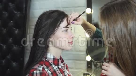 一位年轻的女化妆师在美容院做美容美丽的黑发女孩视频的预览图