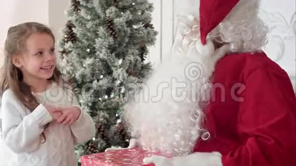 圣诞老人送给一个可爱的小女孩一份包装精美的礼物视频的预览图