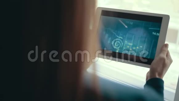 女孩使用平板电脑跟踪图表和股票交易所在后台监控鲜花视频的预览图