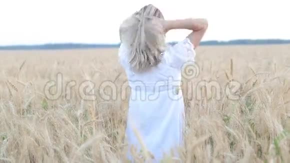 美丽的年轻女子站在一个举起手臂的田野里视频的预览图