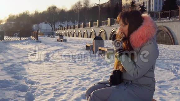 年轻女子在冬季街头吃汉堡视频的预览图