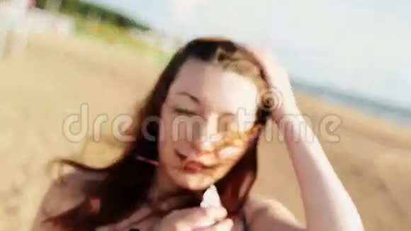 海滩上有花的年轻女孩在镜头里看晴天无忧无虑人们视频的预览图