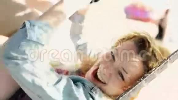快乐粗心的女孩在沙滩上的吊床上摇摆在镜头中微笑阳光明媚免费视频的预览图