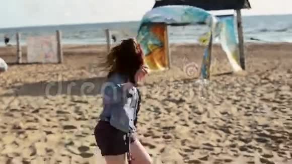 快乐的年轻女孩在海滩上奔跑对着镜头微笑把夹克脱了夏日视频的预览图