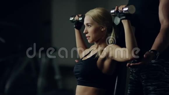 教练帮助女人在健身馆用哑铃锻炼视频的预览图