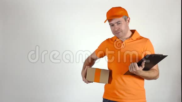 穿橙色制服的送货员给了一个小包裹浅灰色背景4K摄影棚拍摄视频的预览图