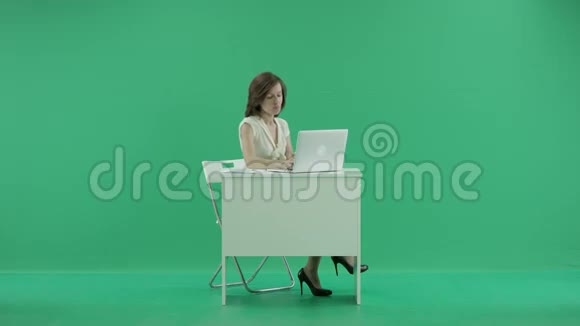 女人坐在桌子旁双脚站在桌子上打电话视频的预览图