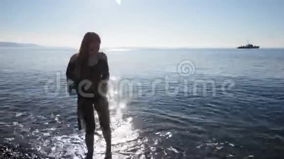 一位美丽的少女在海滨收集鹅卵石的广角镜头视频的预览图