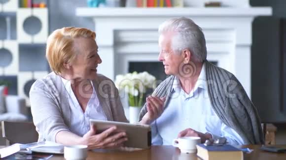 老年夫妇用平板电脑上网冲浪快乐的老人使用平板电脑视频的预览图