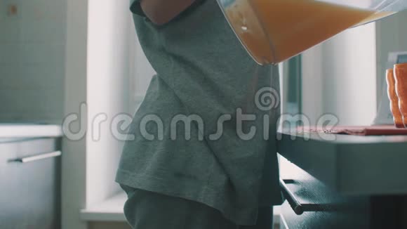 从侧面看年轻女孩把果汁从罐子里倒入玻璃杯把它洒在桌子上视频的预览图