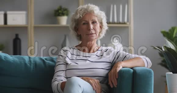 幸福的老太太坐在沙发上看着摄像机视频的预览图
