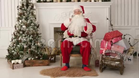 圣诞老人坐在圣诞树旁打电话视频的预览图