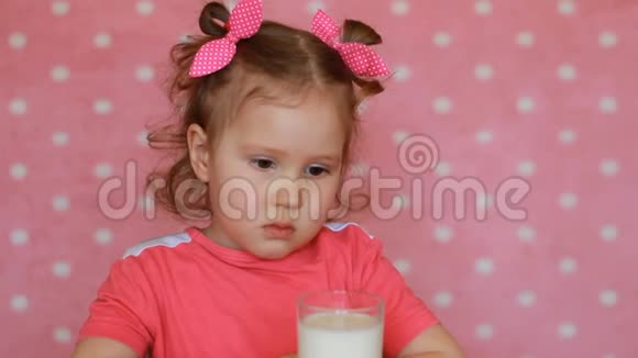 孩子喝牛奶一个漂亮的小女孩手里拿着一杯酒喝着视频的预览图