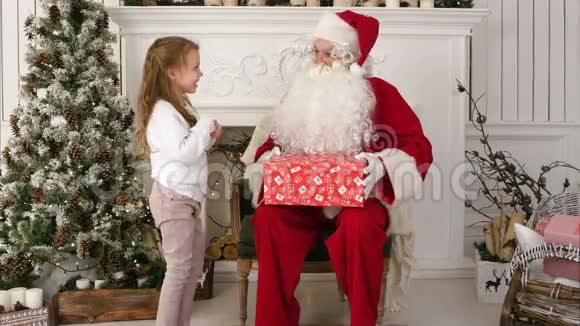 圣诞老人送给一个可爱的小女孩一份包装精美的礼物视频的预览图