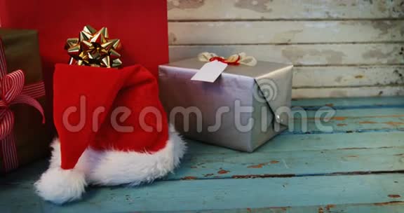 木制木板上的包装礼品和圣诞帽视频的预览图