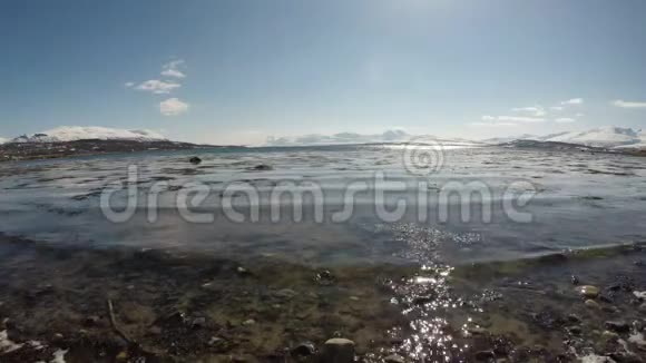 明媚的春日晴朗的蓝天海浪拍打着岩石海岸视频的预览图