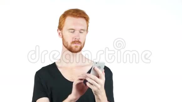 年轻的红头发男子手持移动智能手机使用应用程序短信视频的预览图