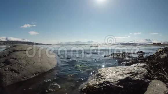 明媚的春日晴朗的蓝天海浪拍打着岩石海岸视频的预览图