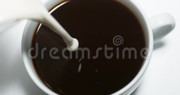 牛奶倒在咖啡杯里在白色背景下视频的预览图