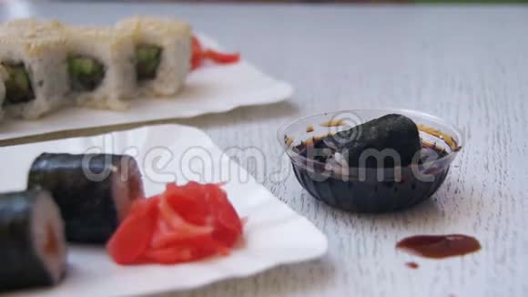 一家日本餐馆的筷子夹着酱油里的诺丽寿司卷慢动作视频的预览图