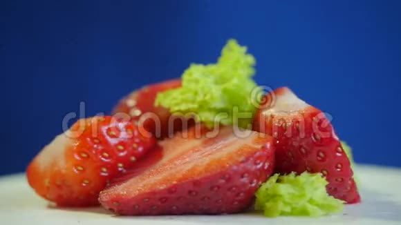 草莓贴在深蓝色背景的白色盘子上一套新鲜草莓慢动作视频的预览图