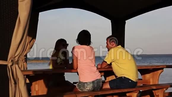 一家人坐在河边的桌子旁父母和孩子花时间视频的预览图