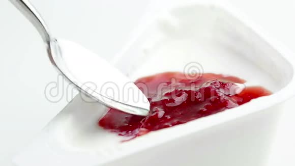 白色背景上汤匙上特写健康草莓奶油和白色酸奶健康营养理念视频的预览图