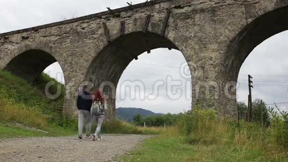 幸福的一对夫妇沿着老高架桥下的路走着视频的预览图