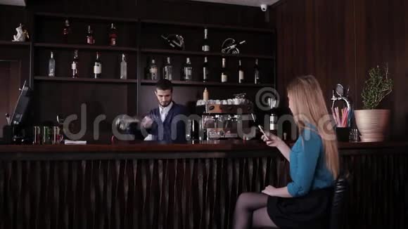 坐在酒吧等酒保准备鸡尾酒的女孩视频的预览图