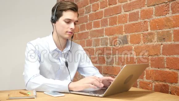 一个年轻有魅力的人在笔记本电脑上工作竖起大拇指呼叫中心视频的预览图