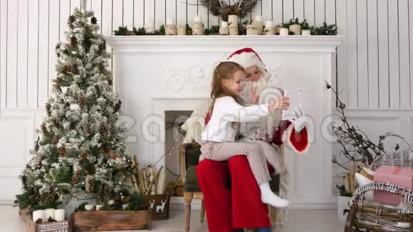 圣诞老人和可爱的小女孩在平板电脑上做圣诞自拍视频的预览图
