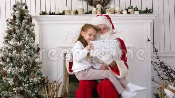快乐的小女孩在平板电脑上展示圣诞老人的惊喜礼物视频的预览图