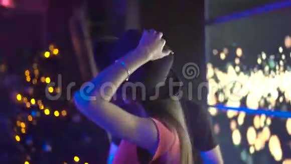 在4K夜总会的面包DJ旁边摆姿势跳舞的迷人女孩视频的预览图