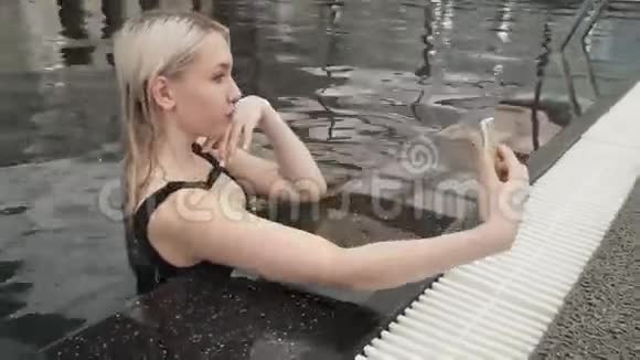 美丽的年轻女孩在iPhone上自拍池中股票视频视频的预览图