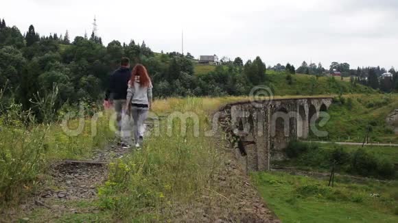一对夫妇沿着山上的老高架桥散步视频的预览图