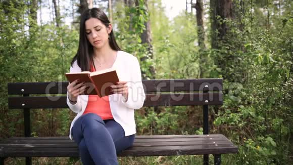 有魅力的年轻女人在公园里拿着旧书滑动滑块视频的预览图