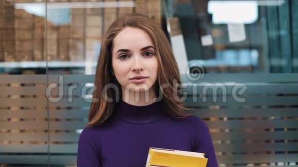 长发女孩站在图书馆的书架前微笑视频的预览图