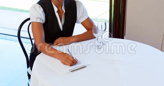 坐在桌边写笔记的女服务员视频的预览图
