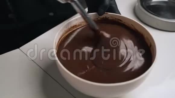 穿黑色制服的女糖果师为巧克力慕斯蛋糕准备奶油舞台烹饪摩丝蛋糕视频的预览图