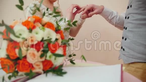 美丽的新娘和英俊的新郎在婚礼花束前戴着金戒指结婚仪式视频的预览图
