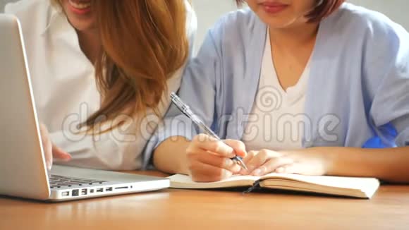 两个年轻的女商人坐在咖啡馆的桌子旁亚洲女性使用笔记本电脑和一杯咖啡视频的预览图